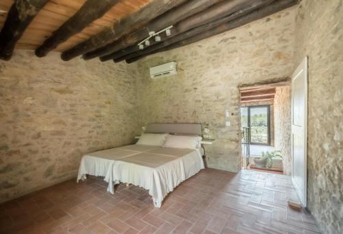 1 dormitorio con 1 cama en una pared de piedra en Flateli Vilopriu, en Vilopríu