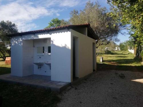 een klein wit gebouw met een deur in het gras bij S&M camping in Sveti Filip i Jakov