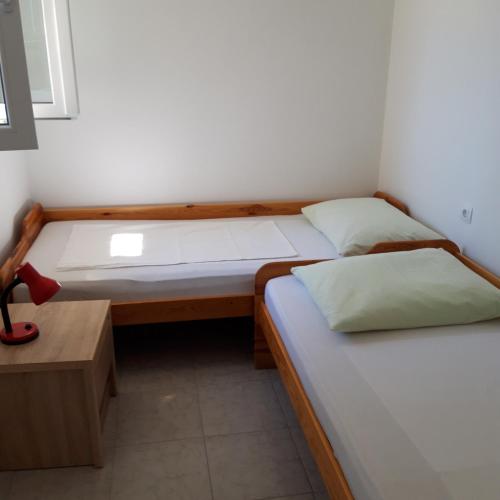 twee bedden in een kleine kamer met een tafel en een bed bij Apartment Lib in Lun