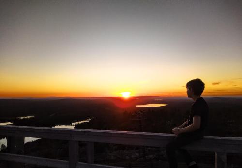 a boy sitting on a ledge watching the sunset at Isokelo Log Apartments in Salla