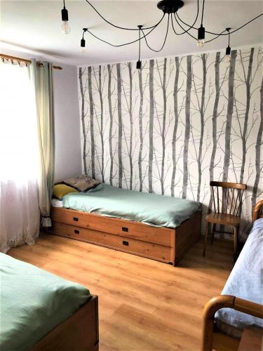a bedroom with two beds and a wall with trees at Domek pod Lipą in Narol