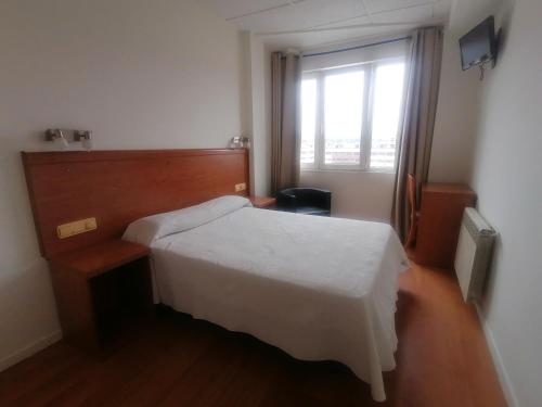 1 dormitorio con cama blanca y ventana en Hotel Besaya en Torrelavega