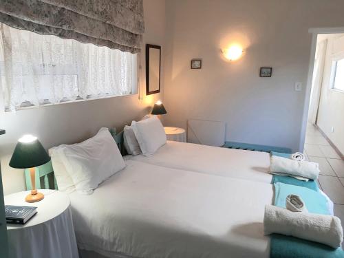 a bedroom with a large white bed and a window at Whale Watchers Inn in Witsand