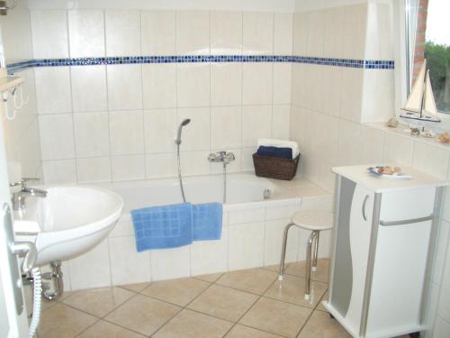 een witte badkamer met een bad en een wastafel bij Ferienhaus Wattenmeerblick in Nordstrand