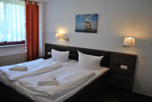 a bedroom with a bed with white sheets and pillows at Strand-Hotel Lobbe in Lobbe