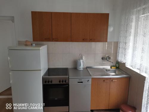 a kitchen with a white refrigerator and a sink at Apartmani Bezek in Ston