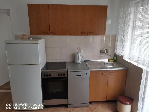 a kitchen with a white refrigerator and a sink at Apartmani Bezek in Ston