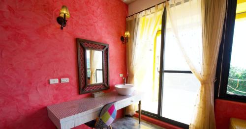 a bathroom with a sink and a mirror on a red wall at 砂點民宿 in Eluan