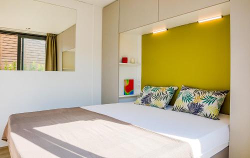 a bedroom with a large bed with a yellow wall at Concept Village Piccola Gardiola in San Felice del Benaco