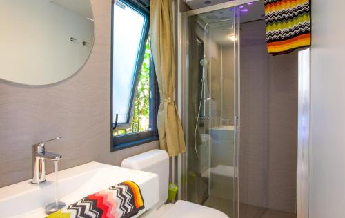 een badkamer met een wastafel, een toilet en een spiegel bij Concept Village Piccola Gardiola in San Felice del Benaco