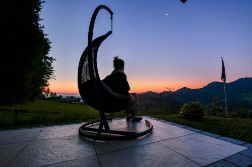 a woman sitting on a sculpture of a bird at sunset at Haus am Sternsberg in Sternenberg
