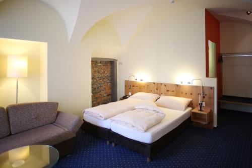 - une chambre avec un lit, une chaise et un canapé dans l'établissement Ambiente Hotel Freieck, à Coire