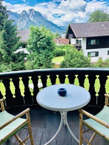 a white table and chairs on a balcony with mountains at Gästehaus Hohe Tannen in Garmisch-Partenkirchen