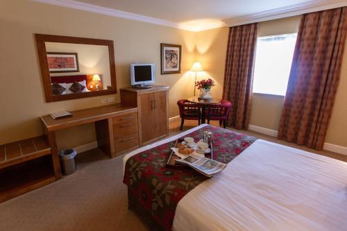 a hotel room with a bed and a desk at Hamlet Court Hotel in Enfield