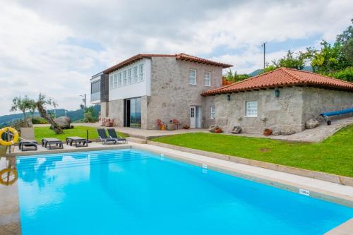 a villa with a swimming pool in front of a house at Casa d' Avó Marcelina - Casas de Campo in Arcos de Valdevez