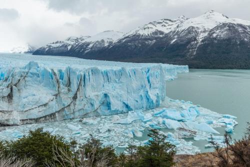 a large iceberg in a body of water with mountains at Mirador del Lago Hotel in El Calafate