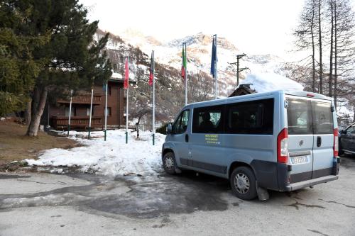a blue van parked in a parking lot with flags at Hotel Rascard in Valtournenche
