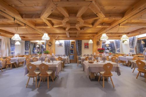 a dining room with tables and chairs and wooden ceilings at Hotel Rascard in Valtournenche