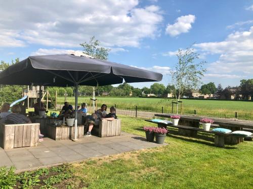 a group of people sitting under an umbrella at De Slaapfabriek vakantiehuis en trainingslocatie in Teuge