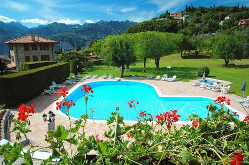 a swimming pool in a yard with mountains in the background at Park Hotel Val Di Monte ***S in Malcesine