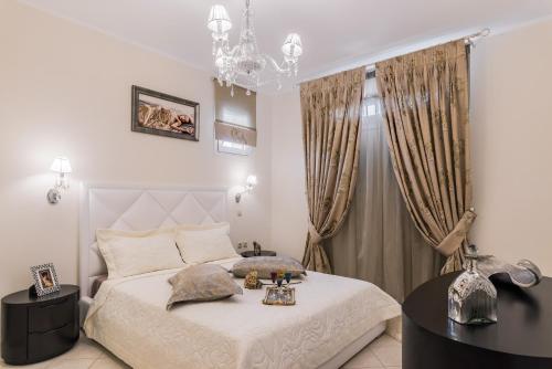 FlókaにあるFaidra Luxury Apartmentのベッドルーム(白いベッド1台、シャンデリア付)