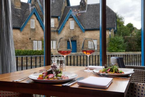 a wooden table with two glasses of wine and food at The Beeley Inn - Chatsworth in Beeley