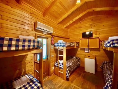 a room with three bunk beds in a cabin at Camping Rural Llanos de Arance in Coto Ríos