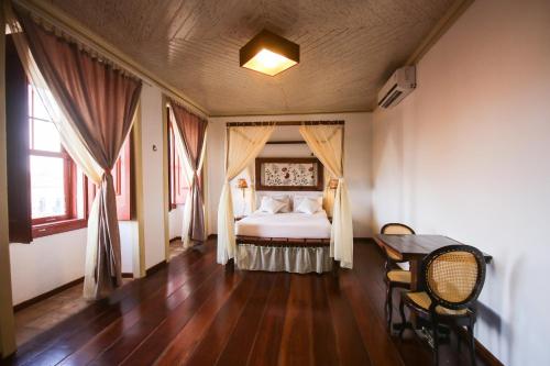 a bedroom with a bed with curtains and a table at Pousada Portas da Amazônia in São Luís