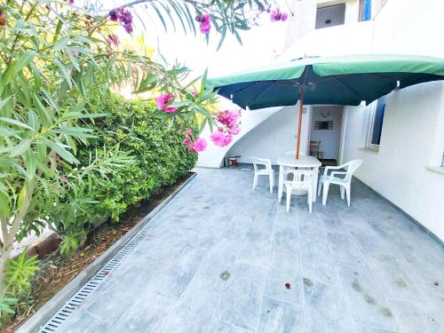 a patio with a table and chairs and an umbrella at Appartamento Nerium - Cala di Seta in Calasetta
