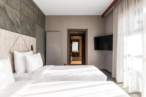 two beds in a hotel room with a television at Nosalowy Park Hotel & Spa in Zakopane