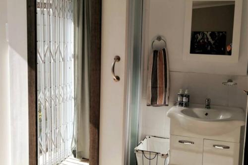a small bathroom with a sink and a window at Chelmsford Cottage in Port Elizabeth