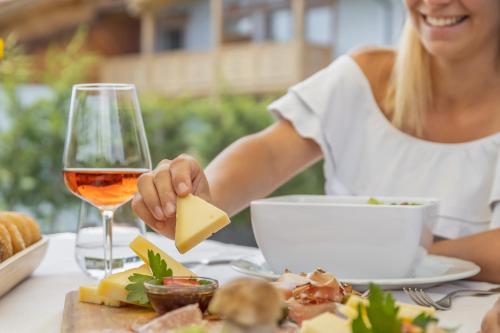 a woman sitting at a table with a glass of wine and cheese at Miraval Hotel in Coredo