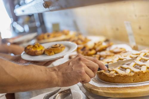 a person holding a knife in front of a table with pies at Miraval Hotel in Coredo