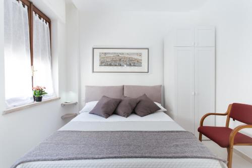 a white bedroom with a bed and a chair at Al centro di Napoli in Naples