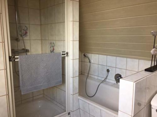 La salle de bains est pourvue d'une baignoire et d'une douche avec rideau de douche. dans l'établissement Ferienwohnung Runge, à Schneverdingen