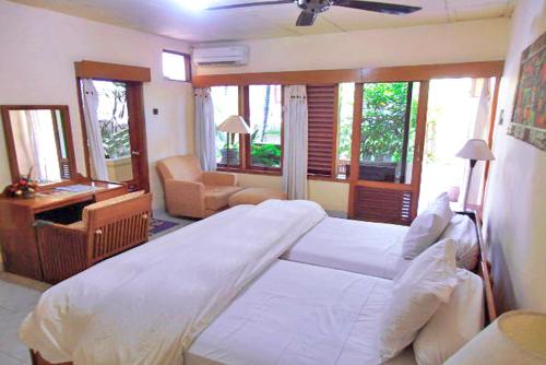 a bedroom with a large bed and a desk at Nakula Familiar Inn in Denpasar
