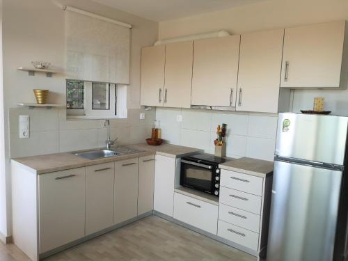 cocina con armarios blancos y nevera de acero inoxidable en Panorama View Apartment 3 en Áyioi Apóstoloi