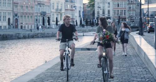 dos personas en bicicleta por una calle junto a un río en Edville Studio en Ghent