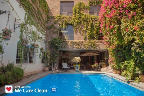 Gómez Palacio的住宿－波薩達德爾里奧貝斯特韋斯特酒店，鲜花盛开的建筑前的游泳池