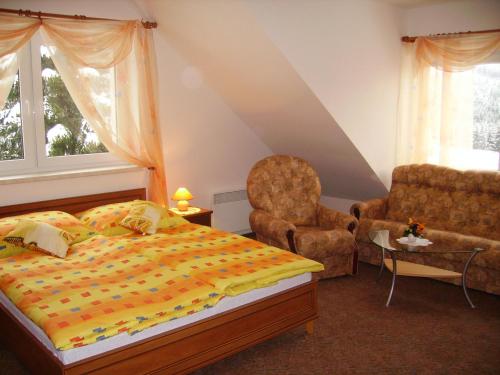 um quarto com uma cama e uma cadeira em Penzion Pod Boubínem em Kubova Huť