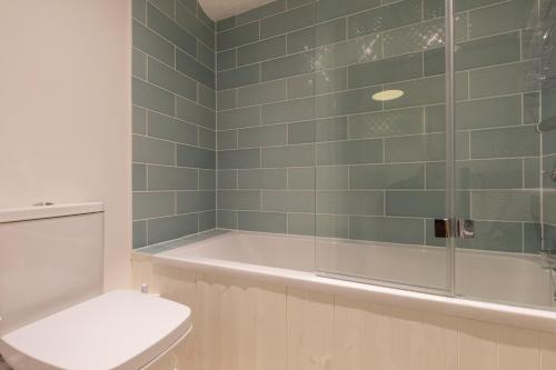 a bathroom with a bath tub and a toilet at Lion Cottage in Holt