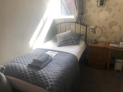 a bedroom with a bed with two pillows and a window at Autumn Leaves Guest House in Windermere