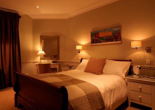 a bedroom with a bed and two lamps and a mirror at The Devonshire Fell Hotel in Burnsall