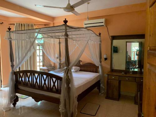 een slaapkamer met een hemelbed en een spiegel bij The Golden Residence in Kegalle