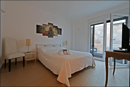 a white bedroom with a bed and a desk at CASA VIRIATO in Ayamonte