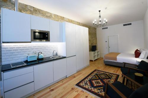 a kitchen with white cabinets and a bed in a room at Trendy Flats Fontainhas in Porto
