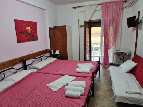 um quarto com duas camas com lençóis vermelhos e toalhas brancas em Gallery em Ammouliani