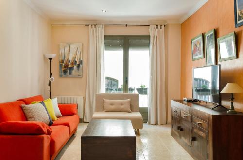 a living room with an orange couch and a tv at Rosa Street Apartment in Girona