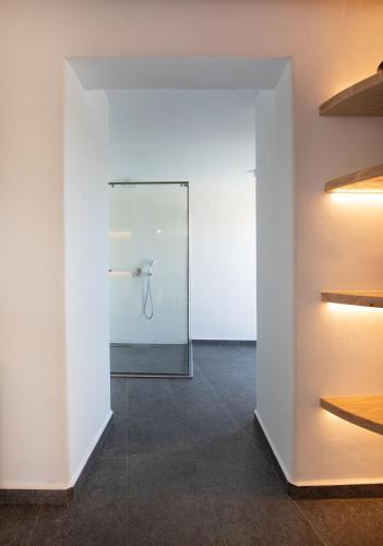 a white room with a glass door with a mirror at Ikies of Mykonos in Mýkonos City