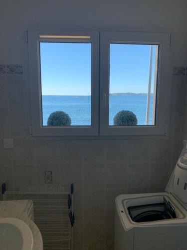 twee ramen in een badkamer met uitzicht op de oceaan bij Le Latania in Sainte-Maxime